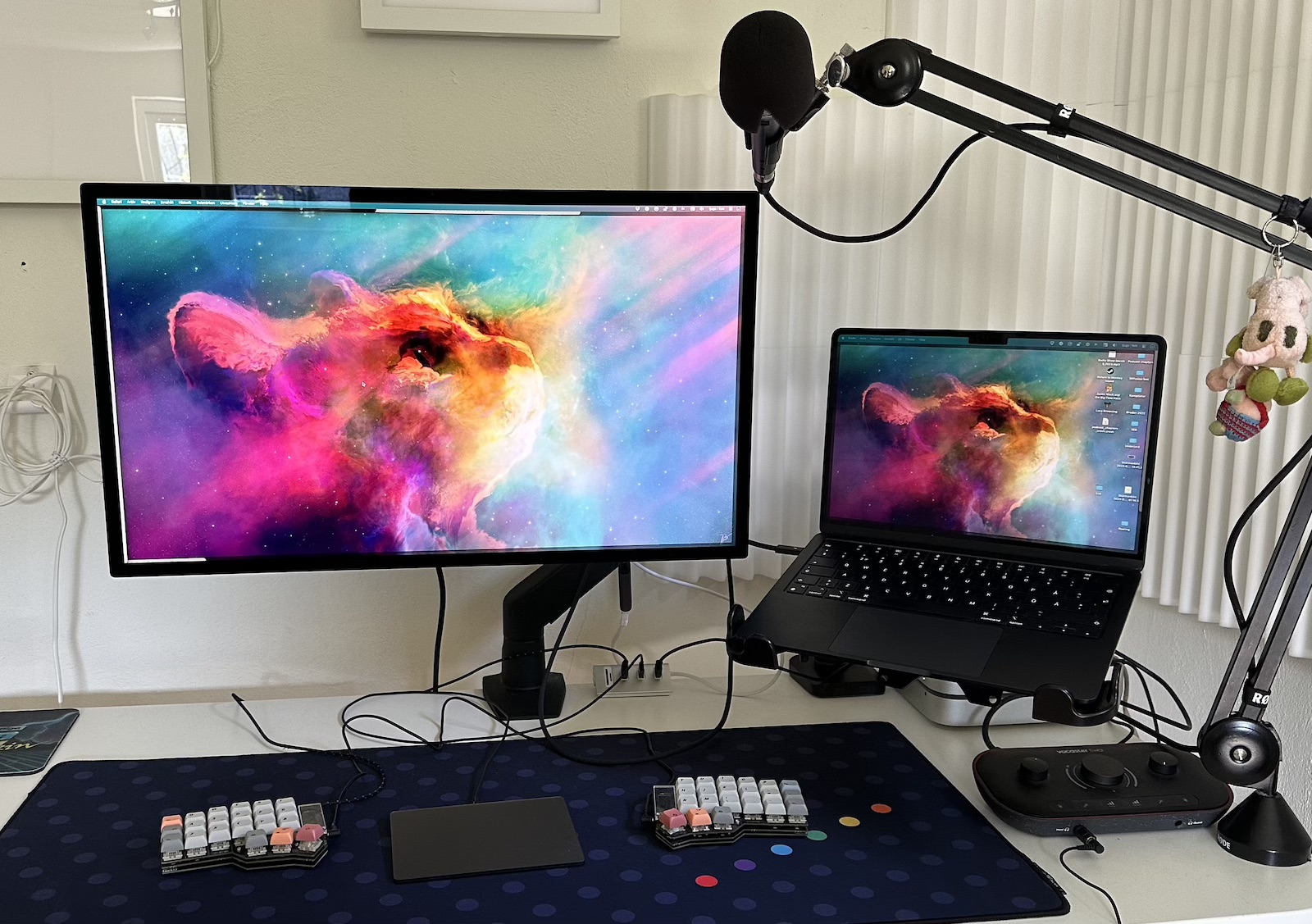 Desk with monitor and laptop on VESA arms, microphone on own arm